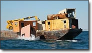 Crane pushing railroad cars into Ocean to facilitate the making of Artificial Reefs